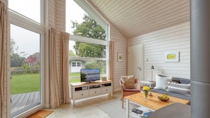 A cozy living room with a television, a sofa, a coffee table, and a large window overlooking a garden. - Awesome Home in Krems Ii/warderbrück With 3 Bedrooms, Sauna and Wifi (Krems II)