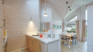 A modern kitchen with wooden cabinetry, a central island, and a dining area with a table and chairs. - Awesome Home in Krems Ii/warderbrück With 3 Bedrooms, Sauna and Wifi (Krems II)