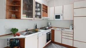 A kitchen with white cabinets, a microwave, a sink, and a coffee maker. - Strandblick 1 (Brodersby)