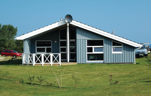 A single-story building with a gabled roof, large windows, and a white porch with a railing.