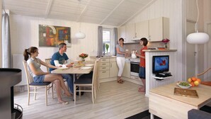 Een moderne keuken met houten kastjes, een eethoek met stoelen en een tv op een standaard.
