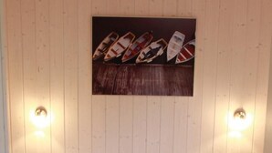 Een tweepersoonsbed met witte lakens in een kamer met houten lambrisering en twee wandlampen.