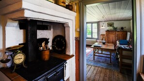 A rustic kitchen with a wood stove, vintage scales, and a rustic dining area with a wooden table and chairs. - Nice Home in Lidköping With 2 Bedrooms, Sauna and Wifi (Lidköping)
