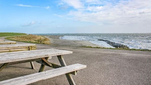 A picnic table on a coastal road with a view of the sea and a grassy area. - Awesome Home in Heinkenszand With Wifi, 4 Bedrooms and Outdoor Swimming Pool (Heinkenszand)