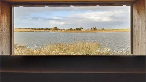 A view of a lake with a lighthouse in the distance, surrounded by grassy areas and trees. - Stunning Home in Breskens With 2 Bedrooms and Wifi (Breskens)