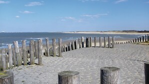 A paved walkway with wooden posts along a beach, leading to the ocean. - Stunning Home in Breskens With 2 Bedrooms and Wifi (Breskens)