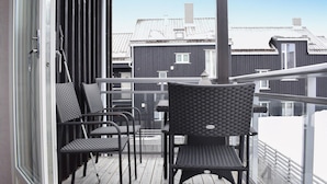 Un balcon avec deux fauteuils en osier et une rambarde en métal.