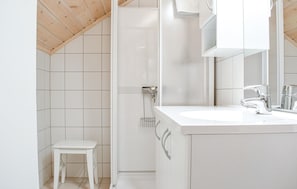 Une salle de bain moderne avec un lavabo blanc, un robinet chromé et un petit tabouret blanc.