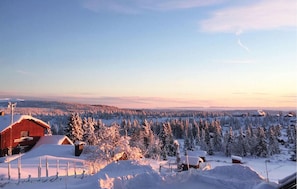 Un paysage enneigé avec une grange rouge et plusieurs cabanes en bois.
