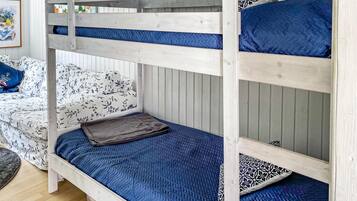 A bunk bed with a blue quilted mattress and a grey blanket.