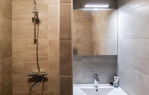 Een badkamer met een douche, een wastafel en een spiegel.