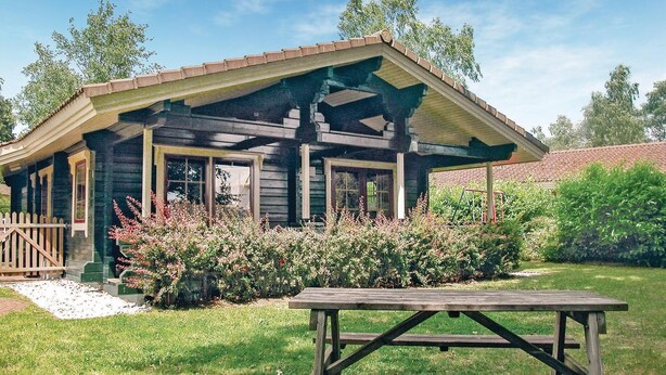 A rustic cabin with a porch, surrounded by lush greenery and a picnic table in the foreground. - Amazing Home in Hulshorst With 3 Bedrooms and Wifi (Hulshorst)