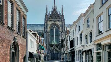 Une rue étroite bordée de bâtiments historiques, dont une imposante église gothique coiffée d’un flèche élancée.