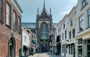 A narrow street flanked by historic buildings, including a prominent Gothic church with a tall spire. - Nice Home in Heinkenszand With 3 Bedrooms, Wifi and Outdoor Swimming Pool (Heinkenszand)