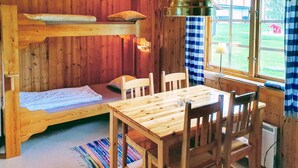 Ein gemütliches Blockhauszimmer mit Etagenbett, Holztisch und Stühlen.