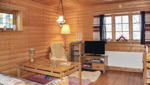 A cozy cabin interior with a wooden interior, a television, a fireplace, and a window with curtains. - Nice Home in Lima With 1 Bedrooms and Wifi (Lima)
