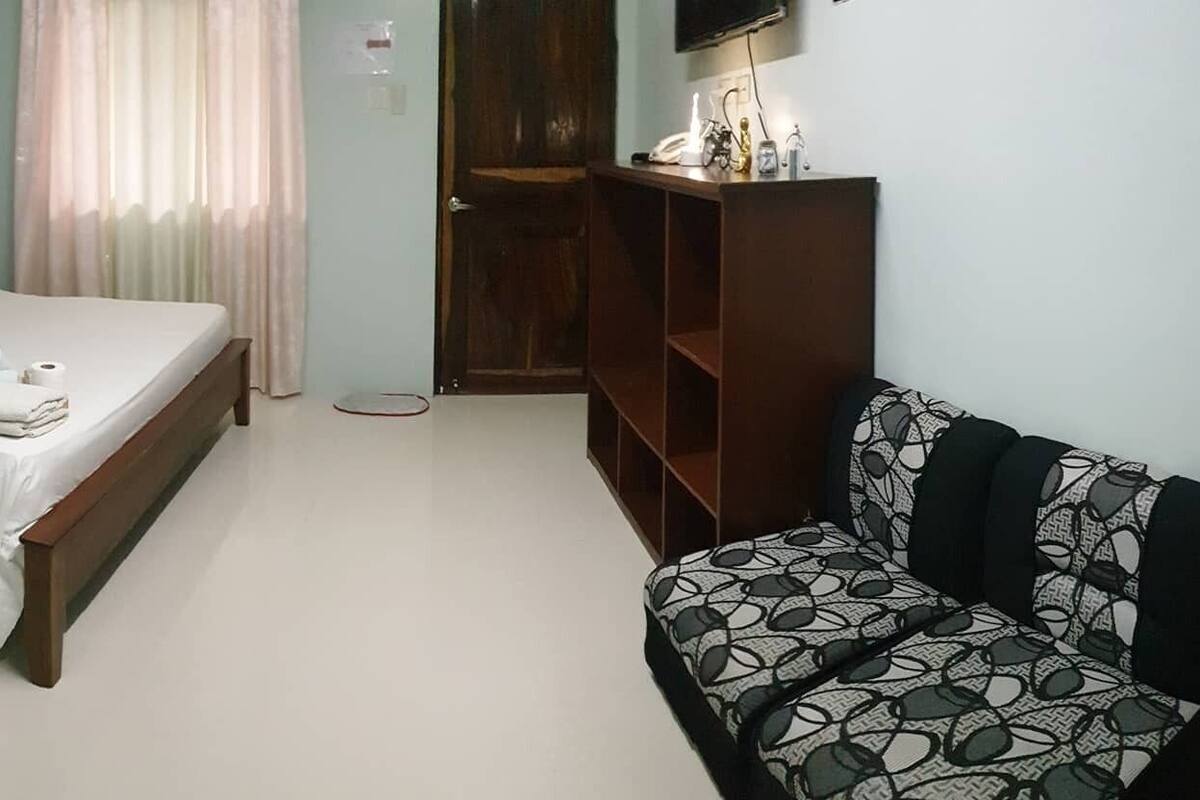 Une chambre à coucher comprenant un lit, une table de chevet, une chaise, une armoire et un mur orné d’une citation décorative.