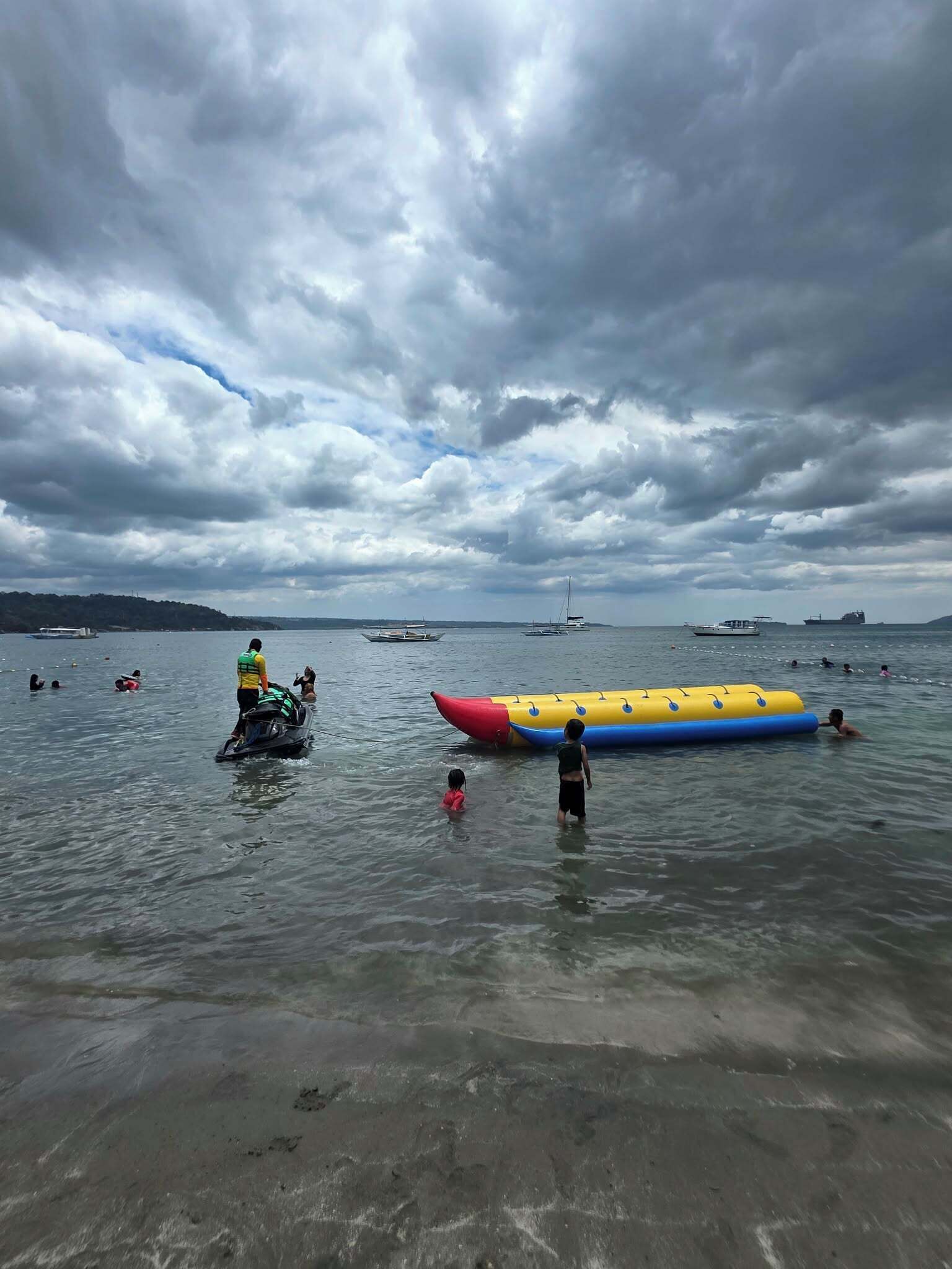 Una masa de agua con barcos, un jet ski y un colorido flotador inflable.