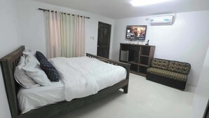 Une chambre à coucher comprenant un lit, une télévision, un canapé et une armoire.