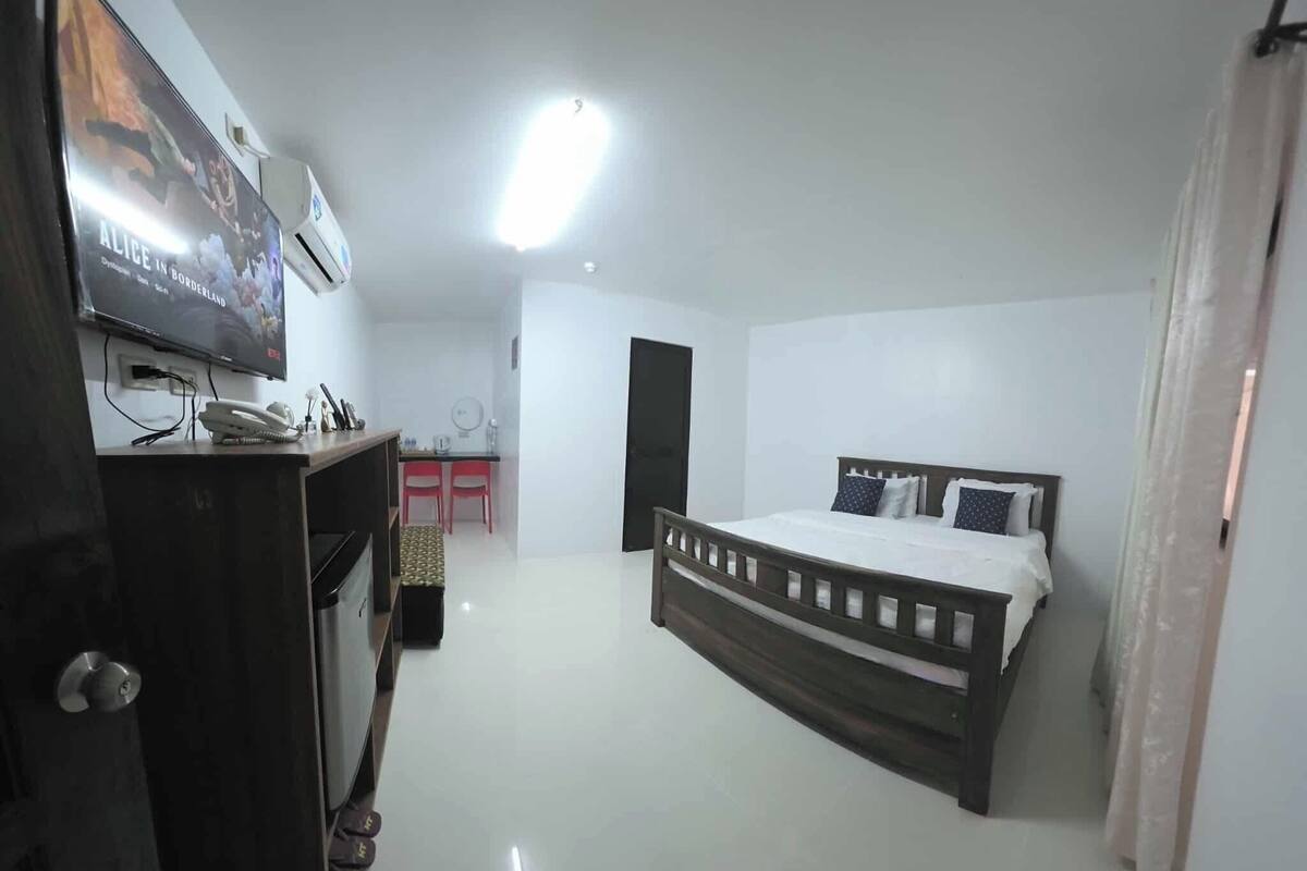 Une chambre à coucher comprenant un lit, un bureau, une chaise, un téléviseur et une armoire.