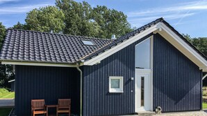 A dark-colored building with a pitched roof, a large window, and two wooden chairs outside. - Nice Home in Krems Ii/warderbrück With 3 Bedrooms and Sauna (Krems II)