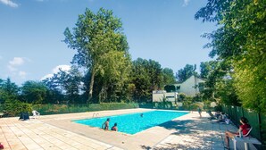 A rectangular swimming pool with a tiled deck, surrounded by trees and a building in the background. - Awesome Home in Bredene With Wifi, Heated Swimming Pool and 3 Bedrooms (Bredene)