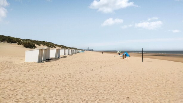 A beach with a row of white beach huts and a tent. - Awesome Home in Bredene With Wifi, Heated Swimming Pool and 3 Bedrooms (Bredene)
