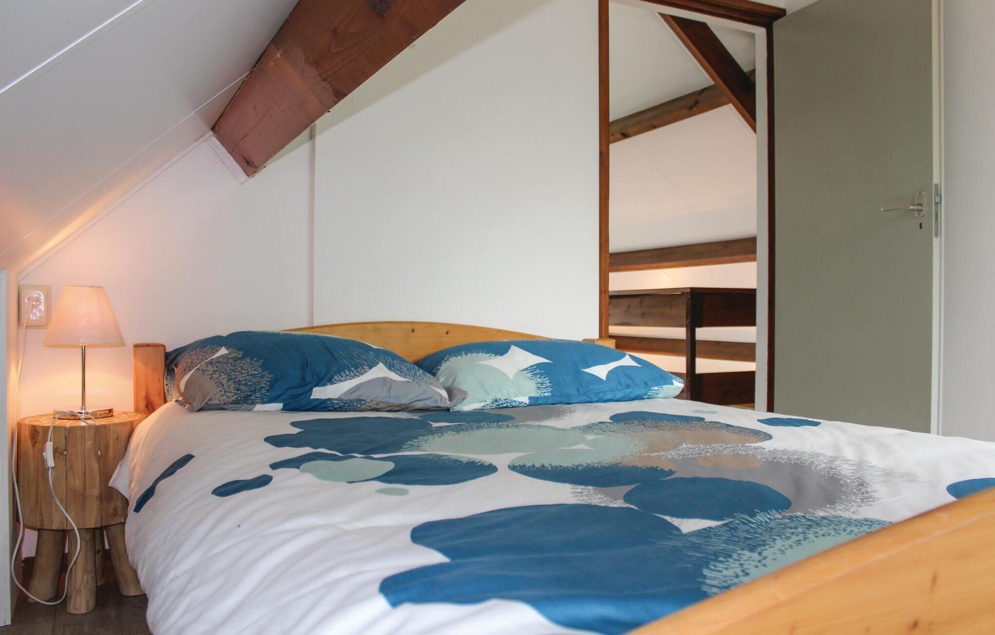 Un dormitorio con una cama, una mesita de noche, una lámpara y un cabecero de madera.