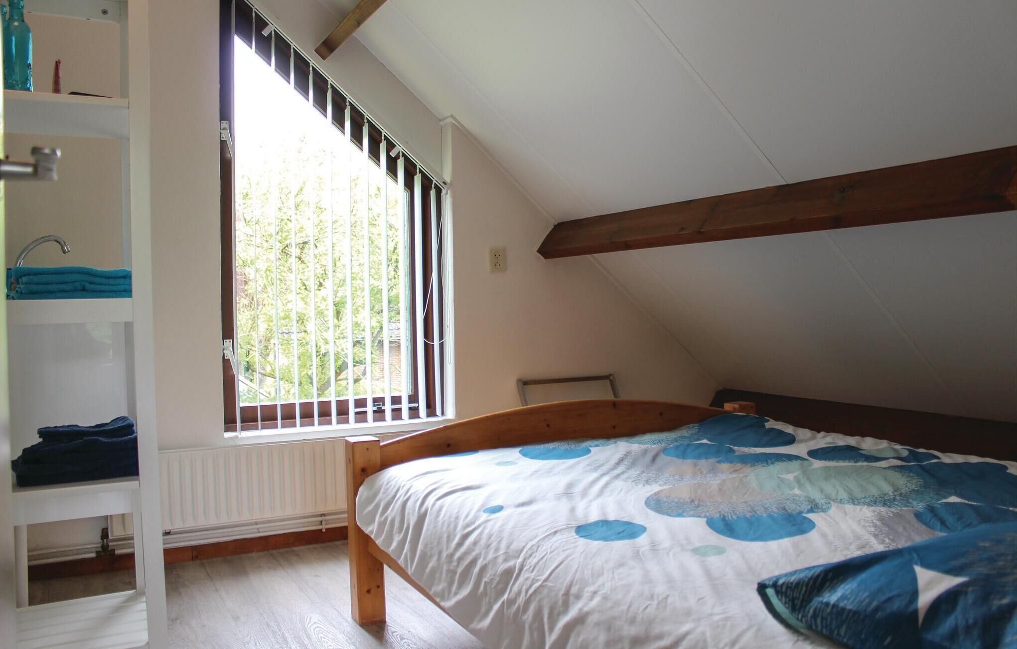 Een slaapkamer met een houten bed, een raam met tralies, een witte radiator en een plank met opgevouwen handdoeken.