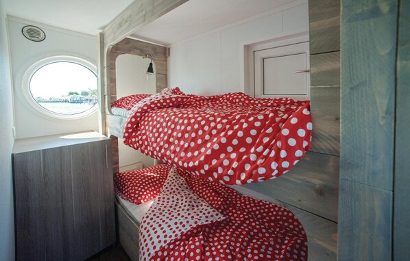 A compact room with a bunk bed, a round window, and a small door. - Aquacabin (Leimuiden)