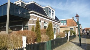 Een klassiek Europees gebouw met een bakstenen gevel, grote ramen en een schuin dak.