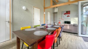 A dining area with a wooden table, colorful chairs, and a modern kitchen in the background. - Awesome Home in Meijel With 3 Bedrooms, Sauna and Wifi (Meijel)