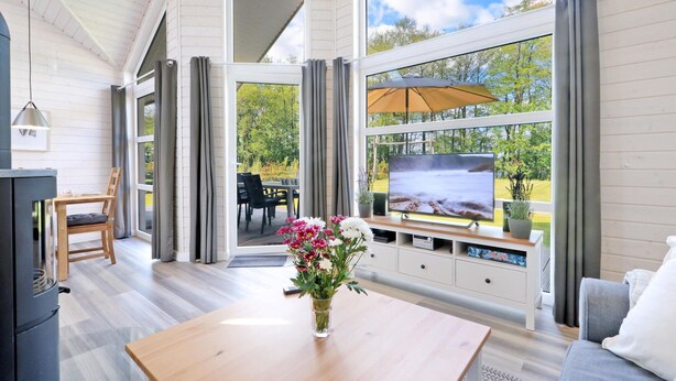 A modern living room with a TV, wooden furniture, and a view of a garden. - Stunning Home in Krems Ii/warderbrück With 3 Bedrooms and Sauna (Krems II)