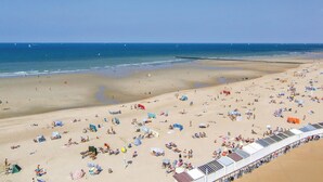 A beach with numerous sunbeds and umbrellas, a clear sky, and a calm sea. - Amazing Apartment in Oostende With Wifi and 1 Bedrooms (Ostend)
