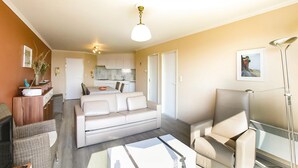 A modern living room with a sofa, armchairs, and a dining area with a table and chairs. There is a kitchen in the background with cabinets and a countertop. - Amazing Apartment in Oostende With Wifi and 1 Bedrooms (Ostend)