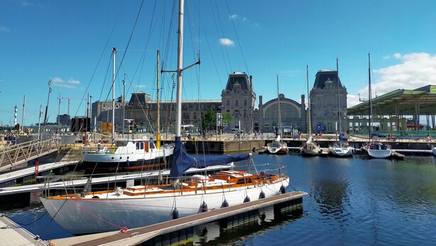 A marina with boats docked, a large building with a clock tower, and a covered area with seating. - Amazing Apartment in Oostende With Wifi and 1 Bedrooms (Ostend)