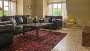Una sala de estar con dos sofás de cuero, una mesa de centro, un tapete estampado y un sillón amarillo.