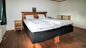 Un dormitorio con cama, mesitas de noche de madera, cómoda y radiador.