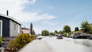 Udsigt over en flod med både, et hus og grøn vegetation.
