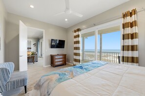 Ein Schlafzimmer mit Bett, Fernseher, Kommode und Blick auf den Strand.