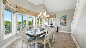 A dining room with a large table, white chairs, and a chandelier.