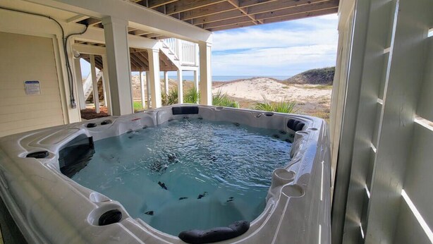 A hot tub with a view of the beach and dunes.