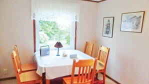 A dining area with a table set for four, a radio, and a lamp. - Amazing Home in Färjestaden With 1 Bedrooms (Farjestaden)