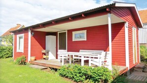 A red wooden house with a porch, a white door, and a small window. - Amazing Home in Färjestaden With 1 Bedrooms (Farjestaden)
