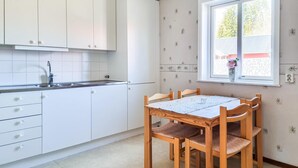 Una cocina con armarios blancos, un lavabo y un ventanal con vistas al verdor.