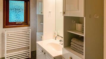 A bathroom with a white sink, a mirror, a towel rack, and a window with a view of trees.
