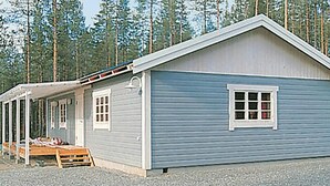 A single-story cabin with a front porch, a small attached shed, and a window.