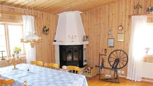 A cozy room with a wooden interior, a fireplace, a spinning wheel, and a dining table set for four.