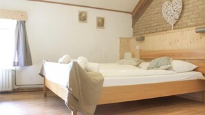 A wooden bed with a headboard, two bedside tables, and a window with curtains. - Vakantiewoning 11 (Simpelveld)