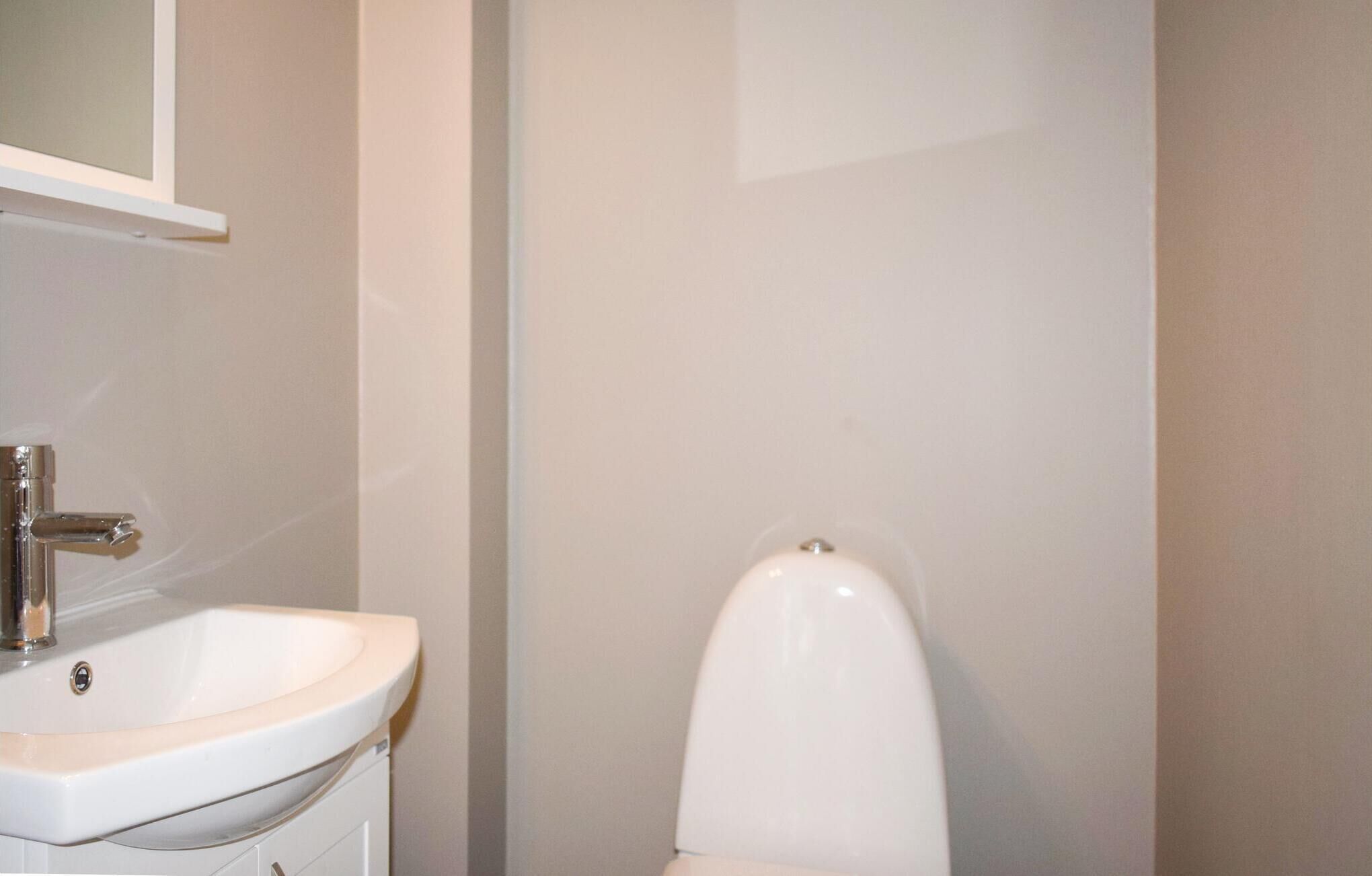 Un baño con lavamanos y retrete blancos.